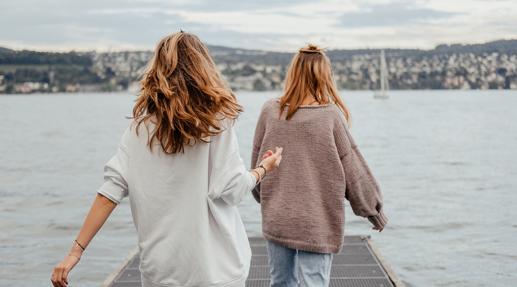two women walking on a dock over water