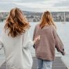 two women walking on a dock over water